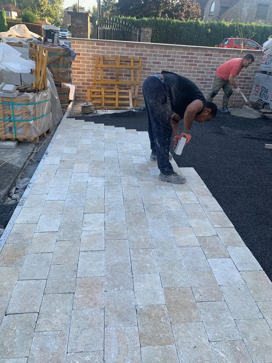 Arbeiders plaatsen natuurstenen kasseien voor een terras