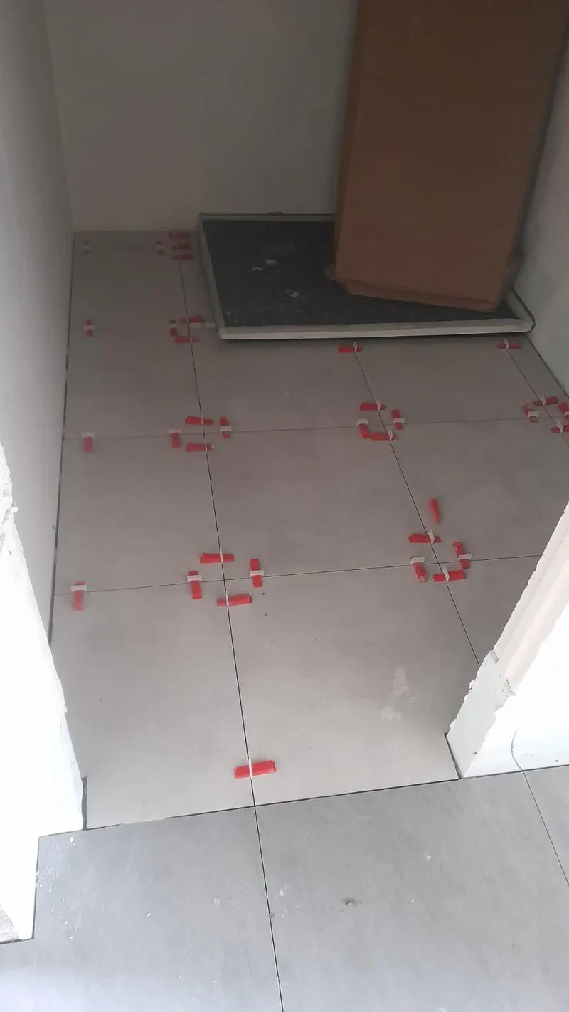Utility room being tiled with large light grey tiles
