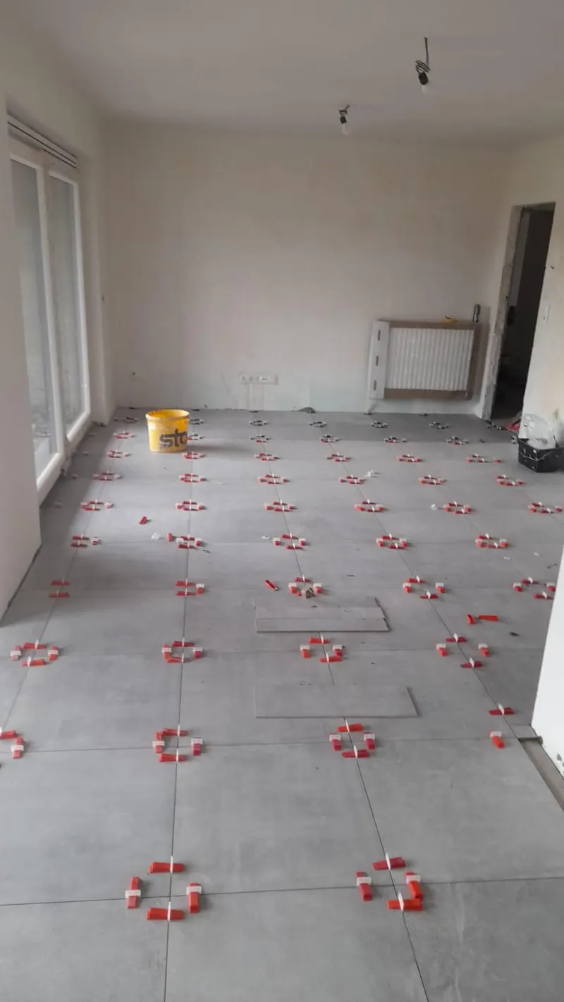 Large-format grey concrete-effect floor with red levelling clips