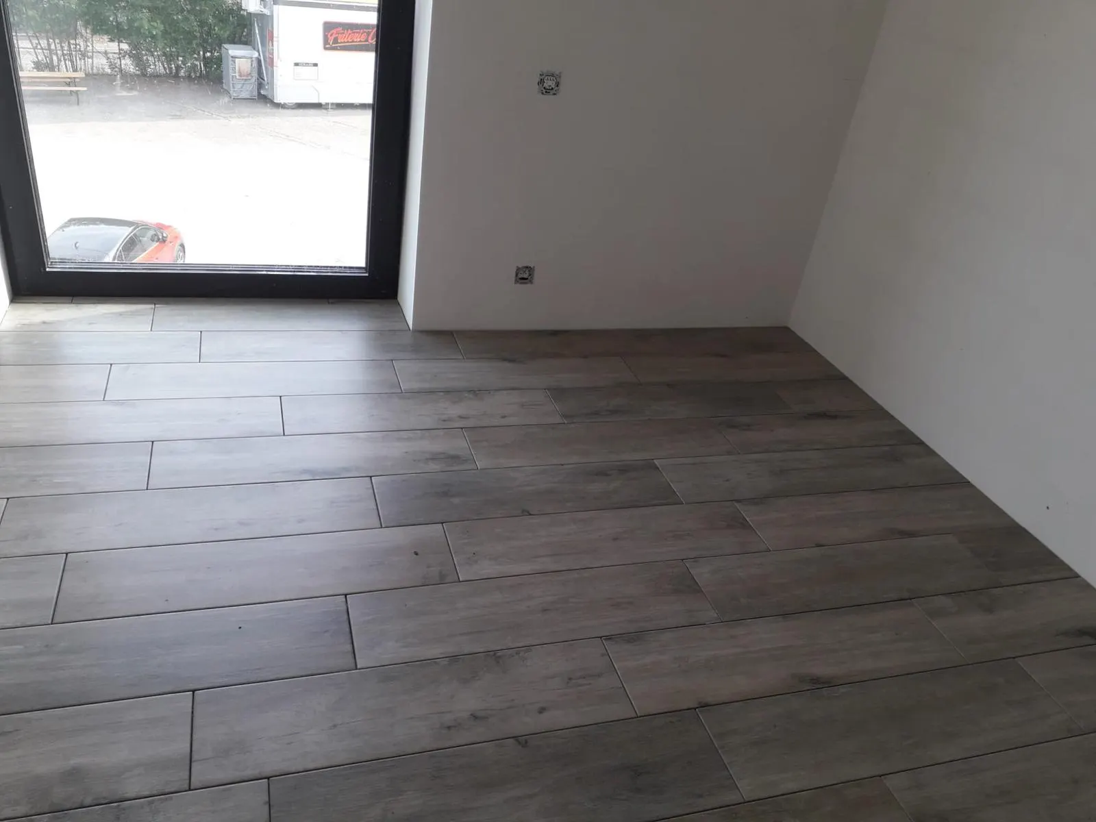 Grey-brown wood-effect floor tiles laid in a staggered pattern