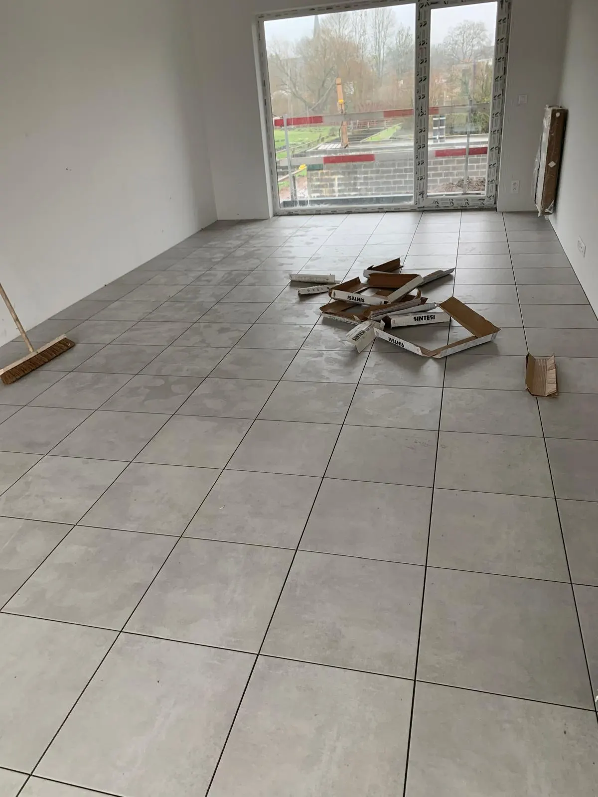 Carrelage de sol gris clair à joints foncés dans un appartement neuf