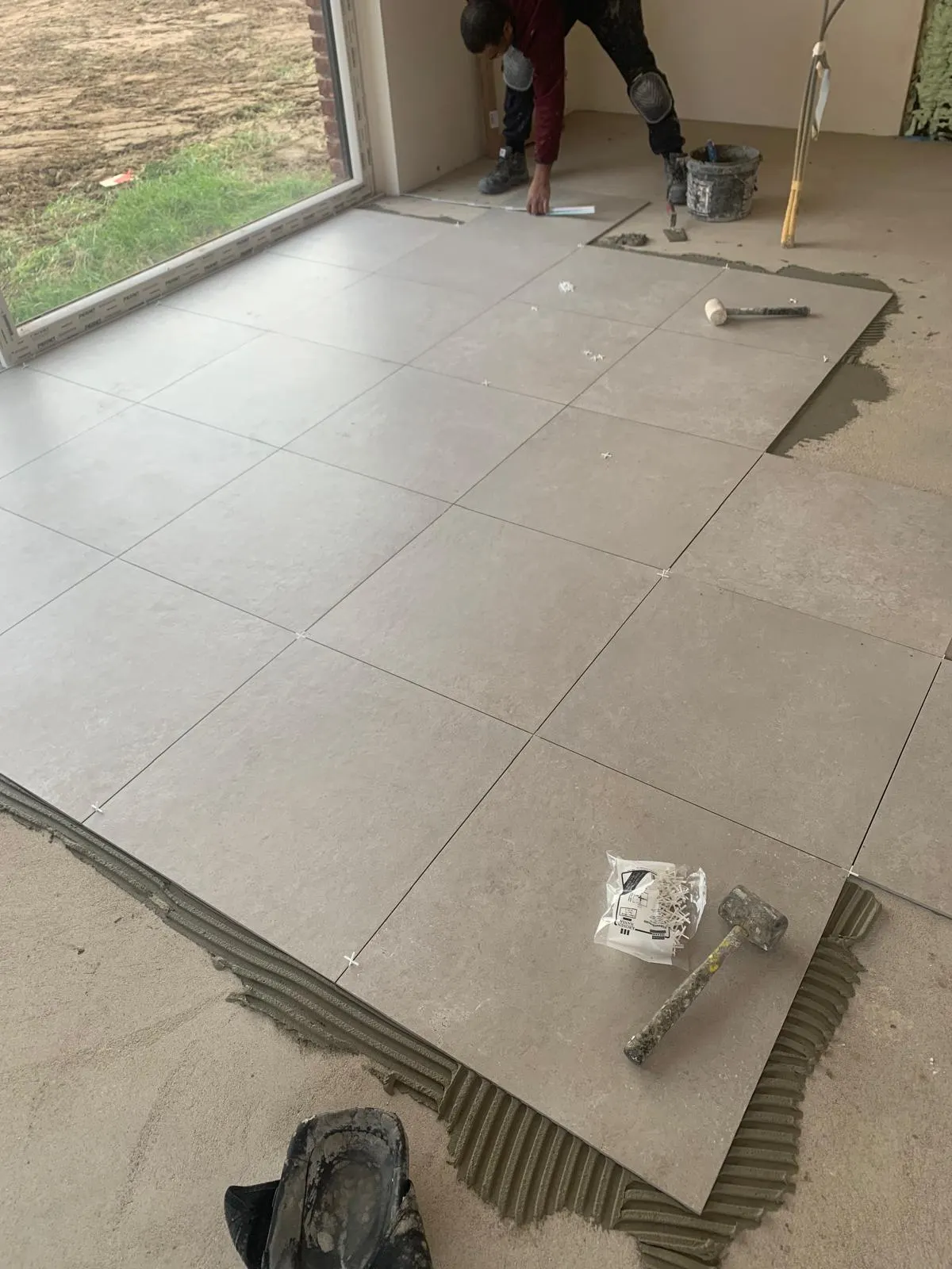Pose de dalles 60x60 gris clair sur colle avec maillet et croisillons