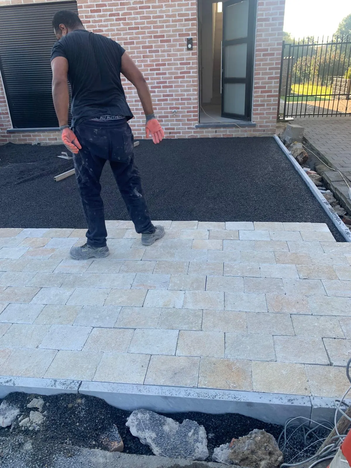 Oprit in natuurstenen kasseien in aanleg voor een bakstenen woning