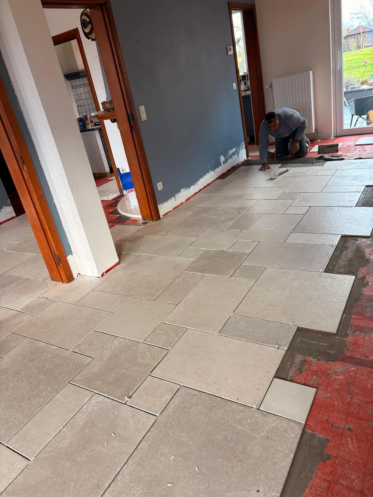 Plaatsing van beige tegels met natuursteenlook in wildverband in een woonkamer