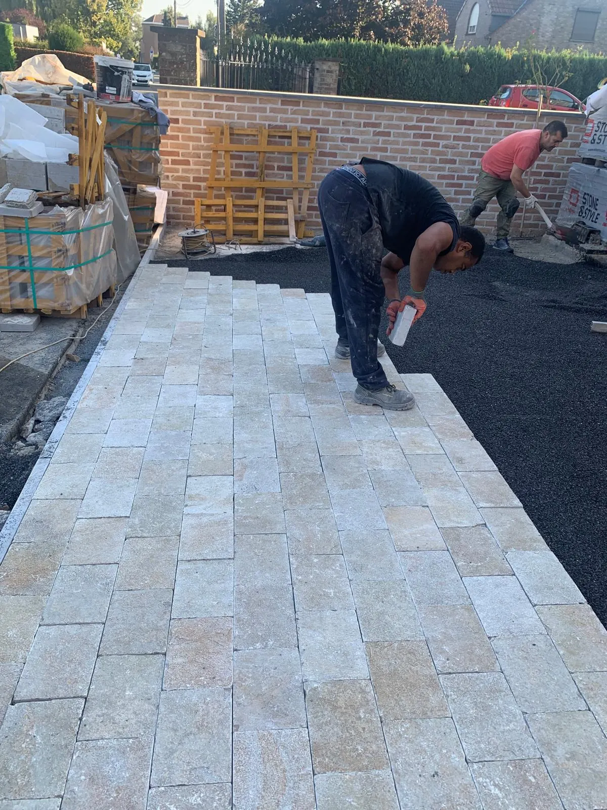 Arbeiders plaatsen natuurstenen kasseien voor een terras